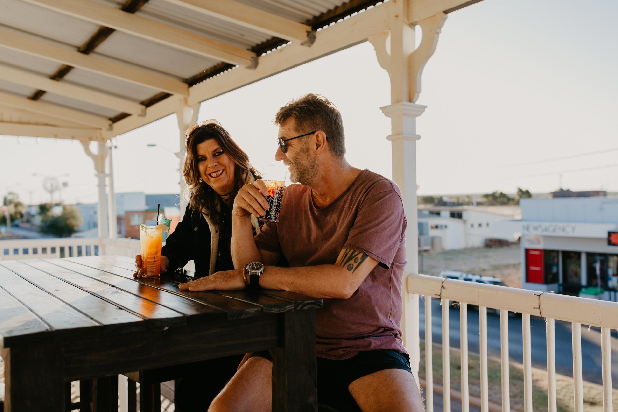 couple on balcony at The Brick Hotel with drinks from the bar